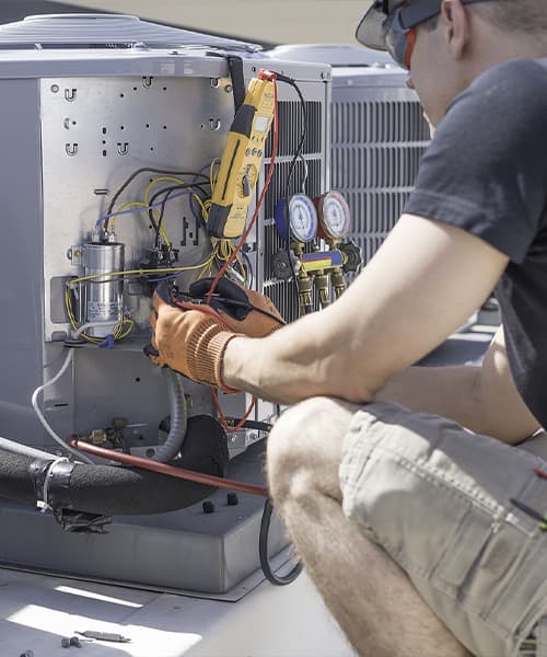 An HVAC technician works on a commercial air conditioning unit