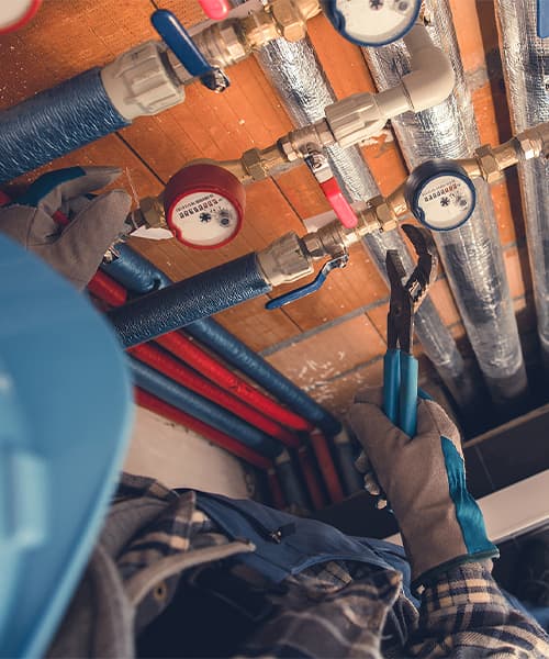 A commercial plumber works with hot and cold water pipes