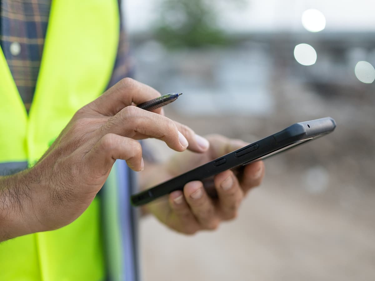 Worker with tablet in safety vest.