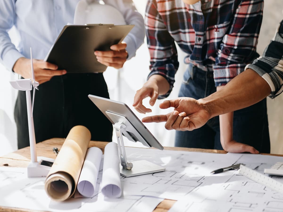 Three individuals collaborating on a construction project with tablet.