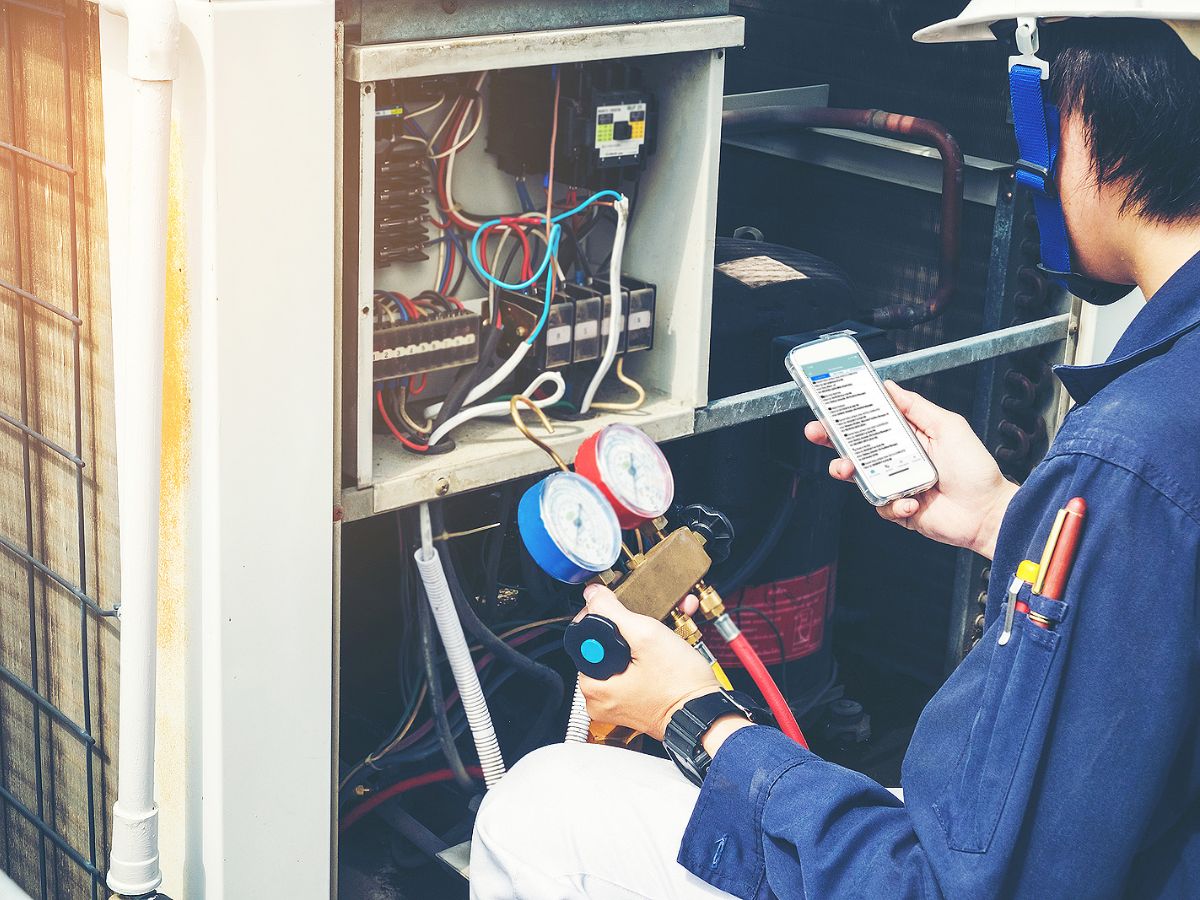 An HVAC contractor working on a project using a phone to help keep on time.